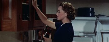Movie still from “The Eddy Duchin Story” (1956), directed by George Sidney – A woman holding a cell phone in her hand; Close Up shot, Low angle