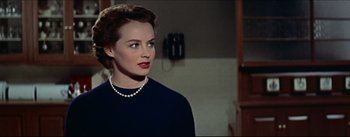 Movie still from “The Eddy Duchin Story” (1956), directed by George Sidney – A woman in a black shirt and a pearl necklace; Close Up shot, Over the shoulder angle