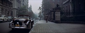 Movie still from “The Eddy Duchin Story” (1956), directed by George Sidney – A man walking down the street with a car behind him; Extreme Wide shot, High angle