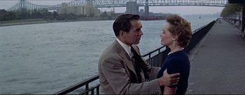 Movie still from “The Eddy Duchin Story” (1956), directed by George Sidney – A man and a woman standing next to each other on a bridge; Medium shot, Over the shoulder angle