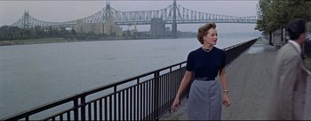 Movie still from “The Eddy Duchin Story” (1956), directed by George Sidney – A woman walking on a bridge over a river; Medium shot, Low angle