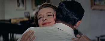 Movie still from “The Eddy Duchin Story” (1956), directed by George Sidney – A woman is hugging a man in front of a mirror; Close Up shot, Over the shoulder angle