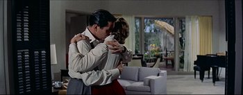 Movie still from “The Eddy Duchin Story” (1956), directed by George Sidney – A man and a woman hugging in a living room; Wide shot, High angle
