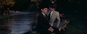 Movie still from “The Eddy Duchin Story” (1956), directed by George Sidney – A man in a suit and a man in a hat; Medium shot, Over the shoulder angle