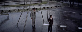 Movie still from “The Eddy Duchin Story” (1956), directed by George Sidney – A man and a boy standing in the rain; Wide shot, High angle
