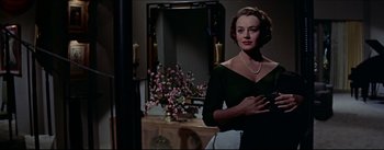 Movie still from “The Eddy Duchin Story” (1956), directed by George Sidney – A woman standing in front of a mirror in a room; Medium shot, Low angle