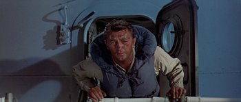 An older man in a life vest standing in an airplane