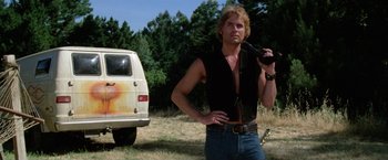 Movie still from “The Enforcer” (1976), directed by James Fargo – A man holding a pipe in his mouth while standing in front of a van; Medium shot, Low angle