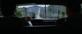 Movie still from “The Enforcer” (1976), directed by James Fargo – A person sitting in a car looking out a window; Wide shot, High angle