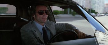 Movie still from “The Enforcer” (1976), directed by James Fargo – A man sitting in the driver's seat of a car wearing sunglasses; Close Up shot, Low angle