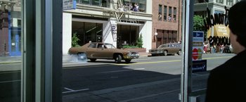 Movie still from “The Enforcer” (1976), directed by James Fargo – A car is driving down the street in front of a building; Wide shot, High angle