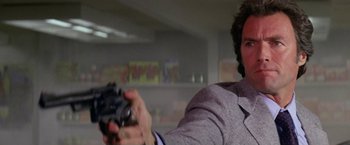 Movie still from “The Enforcer” (1976), directed by James Fargo – A man in a suit holding a camera in a room; Close Up shot, Low angle
