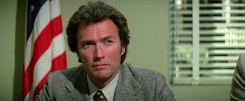Movie still from “The Enforcer” (1976), directed by James Fargo – A person wearing a suit and tie; Close Up shot, Low angle