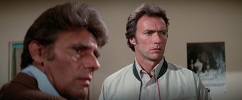 Movie still from “The Enforcer” (1976), directed by James Fargo – A man standing next to another man in front of a wall; Close Up shot, Over the shoulder angle