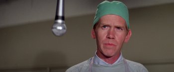 Movie still from “The Enforcer” (1976), directed by James Fargo – A man wearing a green surgical cap and a white shirt; Close Up shot, Low angle