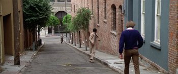 Movie still from “The Enforcer” (1976), directed by James Fargo – A man walking down the sidewalk of a city street; Wide shot, Over the shoulder angle