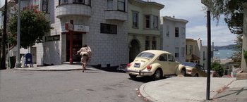 Movie still from “The Enforcer” (1976), directed by James Fargo – A person running down a street with a car parked in front of it; Wide shot, High angle