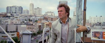 Movie still from “The Enforcer” (1976), directed by James Fargo – A person wearing headphones near a city; Medium shot, Low angle