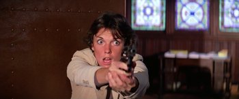 Movie still from “The Enforcer” (1976), directed by James Fargo – A woman holding a gun in a room; Close Up shot, Low angle