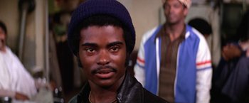 Movie still from “The Enforcer” (1976), directed by James Fargo – A person wearing a jacket and a hat; Close Up shot, Over the shoulder angle