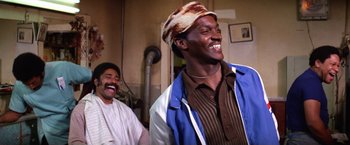 Movie still from “The Enforcer” (1976), directed by James Fargo – Two men laughing and smiling in a room; Medium shot, Low angle