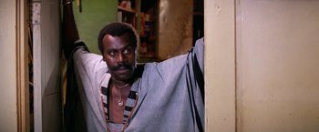 Movie still from “The Enforcer” (1976), directed by James Fargo – A man with a beard and mustache is leaning against a wall; Close Up shot, Low angle