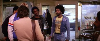 Movie still from “The Enforcer” (1976), directed by James Fargo – A couple of men standing next to each other in a room; Medium shot, Over the shoulder angle