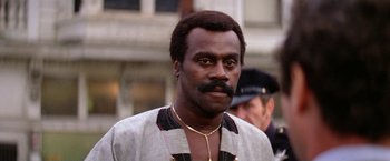 Movie still from “The Enforcer” (1976), directed by James Fargo – A man with a mustache and a beard is looking at the camera; Close Up shot, Low angle