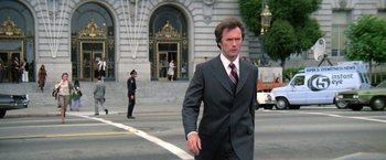 Movie still from “The Enforcer” (1976), directed by James Fargo – A man wearing a suit and tie walking down a street; Wide shot, Low angle