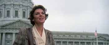 Movie still from “The Enforcer” (1976), directed by James Fargo – A woman standing in front of a large building; Close Up shot, Low angle