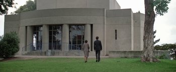 Movie still from “The Enforcer” (1976), directed by James Fargo – A man and a woman walking in front of a building; Extreme Wide shot, Low angle
