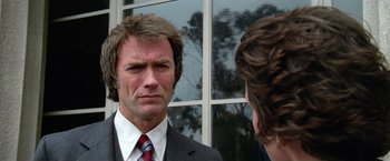 Movie still from “The Enforcer” (1976), directed by James Fargo – A person wearing a suit and tie; Close Up shot, Over the shoulder angle