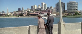 Movie still from “The Enforcer” (1976), directed by James Fargo – A man and a woman standing on a wall near a body of water; Extreme Wide shot, High angle