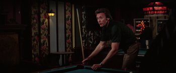 Movie still from “The Enforcer” (1976), directed by James Fargo – A man is playing a game of billiards; Medium shot, Over the shoulder angle