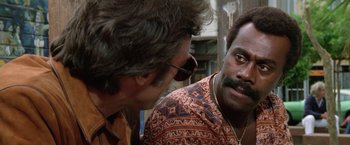 Movie still from “The Enforcer” (1976), directed by James Fargo – Two men talking to each other on the street; Close Up shot, Over the shoulder angle