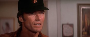 Movie still from “The Enforcer” (1976), directed by James Fargo – A person wearing a baseball cap; Close Up shot, Over the shoulder angle