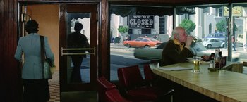 Movie still from “The Enforcer” (1976), directed by James Fargo – Two people are sitting at a table in front of a closed sign; Wide shot, Over the shoulder angle
