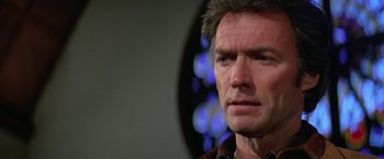 Movie still from “The Enforcer” (1976), directed by James Fargo – A man's face in front of a blue background; Close Up shot, Low angle