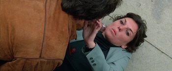 Movie still from “The Enforcer” (1976), directed by James Fargo – A man is putting a tie on a woman's neck; Close Up shot, Overhead angle
