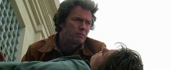 Movie still from “The Enforcer” (1976), directed by James Fargo – A person leaning over another person; Close Up shot, Low angle