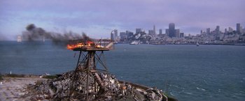 Movie still from “The Enforcer” (1976), directed by James Fargo – A view of a city from the water with a fire burning in it; Extreme Wide shot, High angle