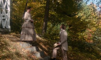 Movie still from “The Europeans” (1979), directed by James Ivory – A man kneeling down next to a woman in a dress; Wide shot, High angle
