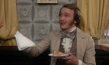 Movie still from “The Europeans” (1979), directed by James Ivory – A man holding a piece of pie in his hands; Medium shot, Over the shoulder angle