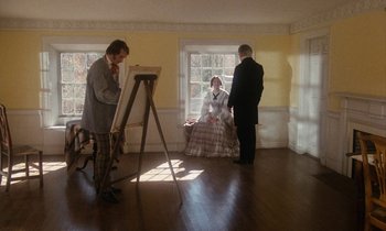 Movie still from “The Europeans” (1979), directed by James Ivory – Three people are standing in front of an easel; Wide shot, High angle