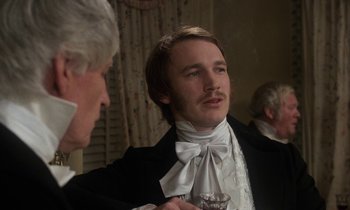 Movie still from “The Europeans” (1979), directed by James Ivory – A man in a suit and a tie holding a wine glass; Close Up shot, Over the shoulder angle
