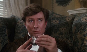 Movie still from “The Europeans” (1979), directed by James Ivory – A person sitting on a couch holding a glass; Close Up shot, Over the shoulder angle