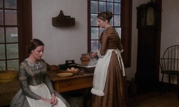 Movie still from “The Europeans” (1979), directed by James Ivory – Two women dressed in period clothing preparing food in an old - fashioned kitchen; Medium shot, High angle