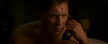 Movie still from “The Exception” (2016), directed by David Leveaux – A shirtless man talking on a phone in the dark; Close Up shot, Low angle