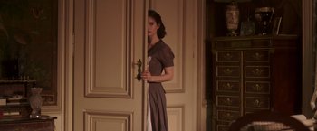 Movie still from “The Exception” (2016), directed by David Leveaux – A woman standing in front of a door holding a knife; Medium shot, High angle