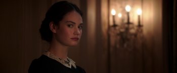 Movie still from “The Exception” (2016), directed by David Leveaux – A young woman with dark hair wearing a black shirt; Close Up shot, Over the shoulder angle